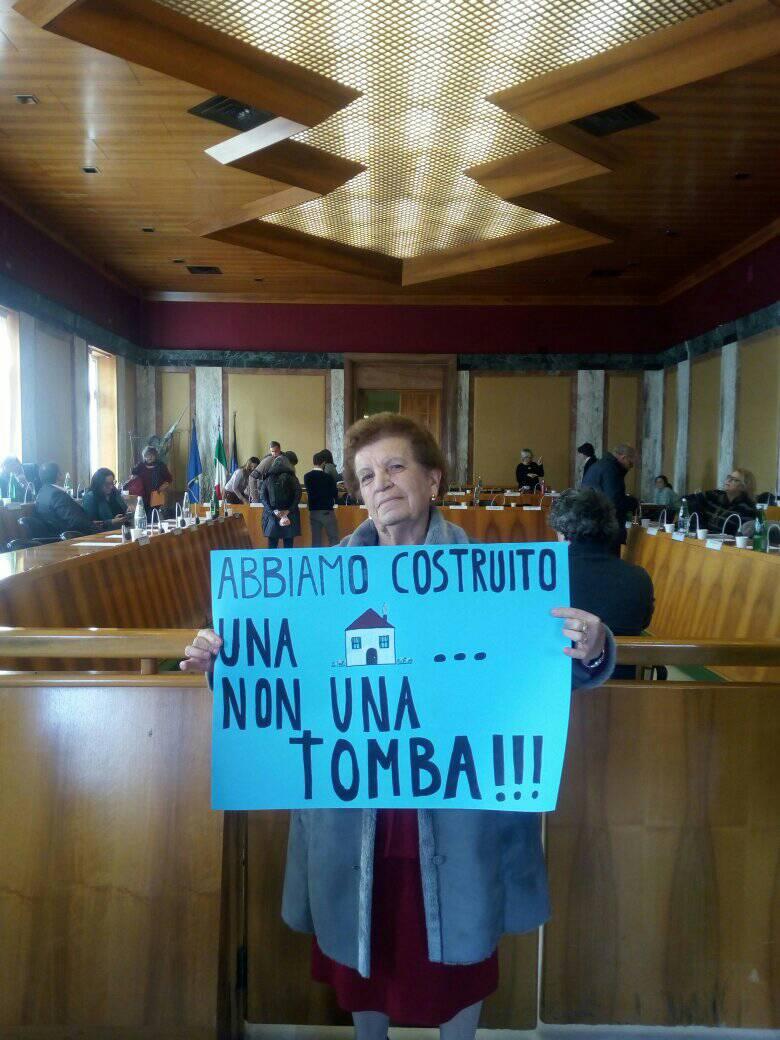 Mamma di Carla Piovesan durante un consiglio comunale con in mano un cartello di protesta.