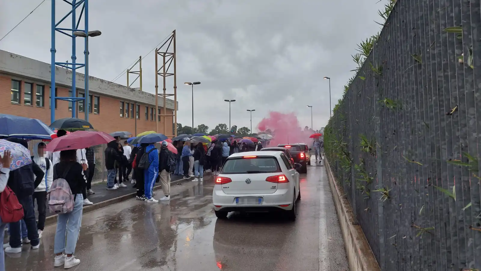 Un fumogeno rosa viene lanciato dai manifestanti fuori dell'Istituto Carlo e Nello Rosselli di Aprilia per protesta